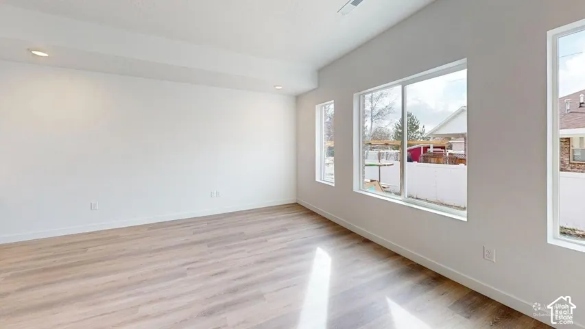 Recessed lighting, light wood-finish flooring, multiple windows, and crisp white walls