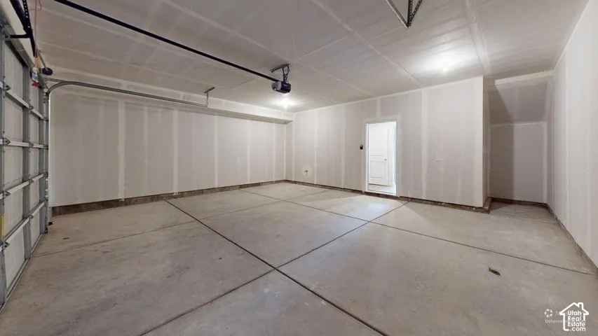 Spacious garage featuring a concrete floor, overhead lighting, and an interior access door