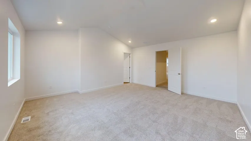 Recessed lighting, light-toned carpeting, white walls, and a large window