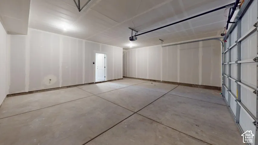 Expansive garage space with concrete flooring, overhead lighting, and an attached garage door
