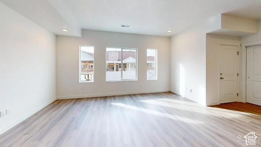 Recessed lighting, wood-finish flooring, white walls, multiple windows, and white interior doors