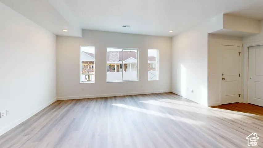 Recessed lighting, light wood-finish flooring, multiple windows, white painted walls, and a sliding door closet