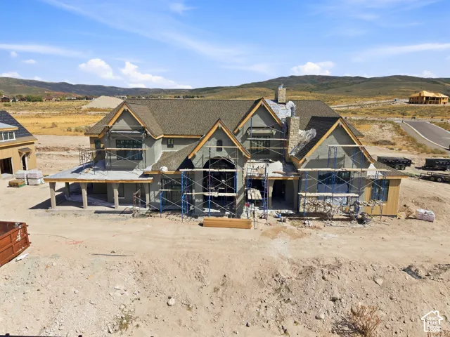 New construction home featuring multiple gable roofs, stucco and stone exterior elements, and visible structural framing