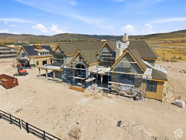 Multi-level roofline with varied material finishes, stone chimney, wood siding accents, and a developing exterior facade