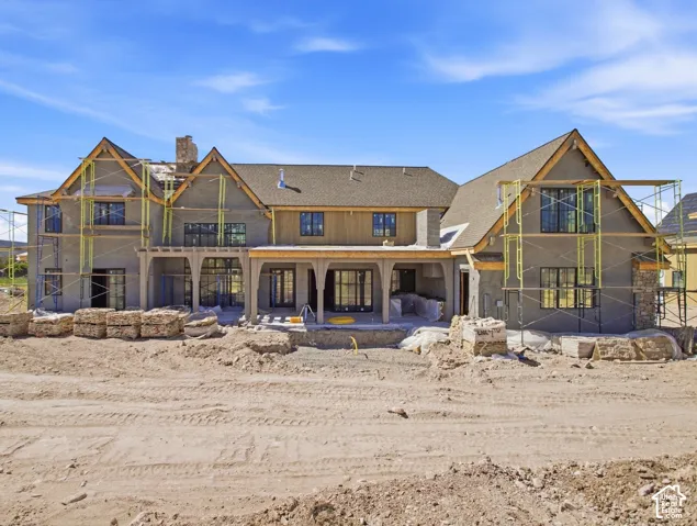 Multiple gable roofs with shingle roofing, expansive stucco exterior, stone accents, numerous windows, and covered patio space