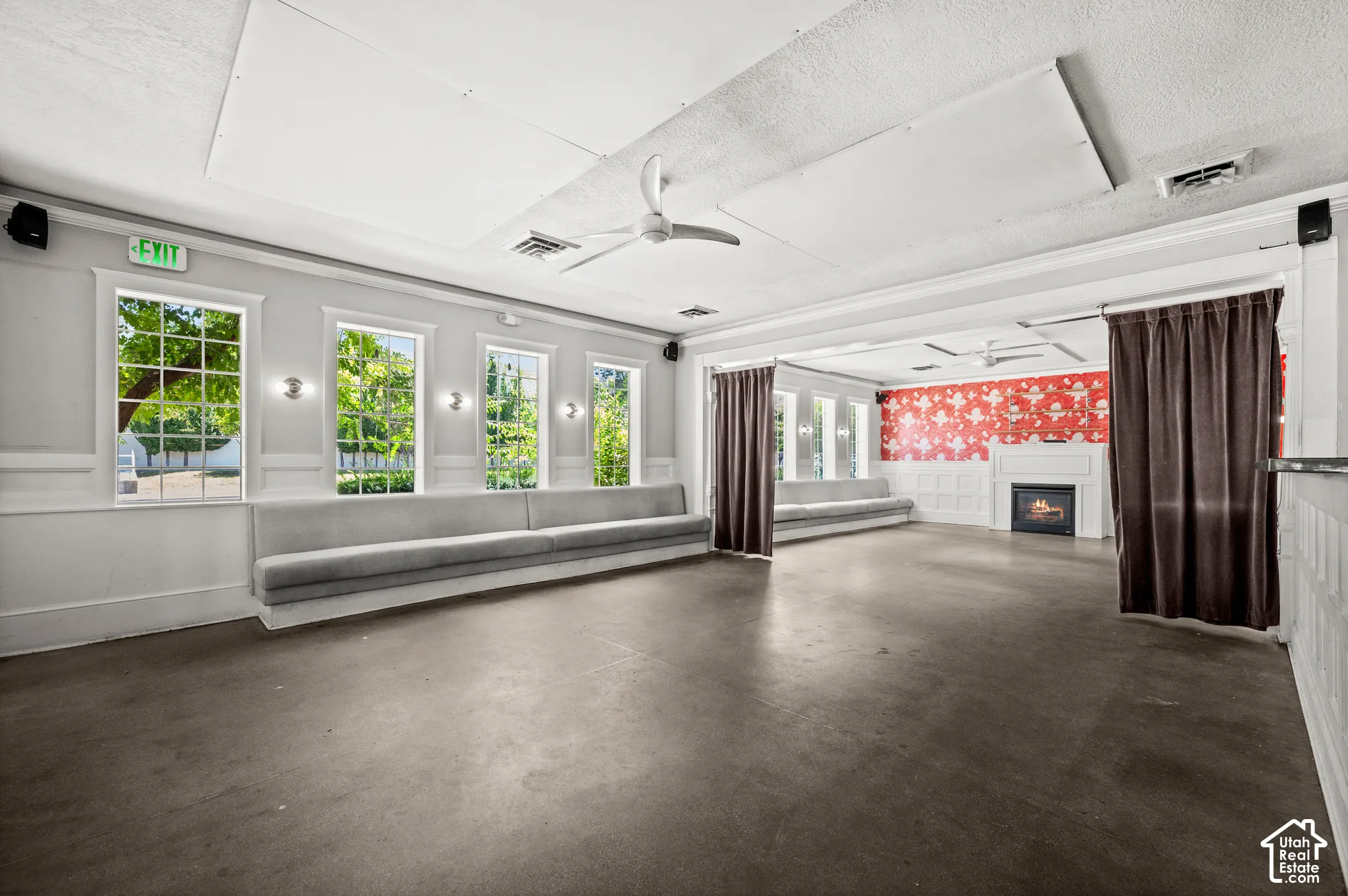 Expansive open-concept room featuring multiple windows, recessed fireplace, and ceiling fans