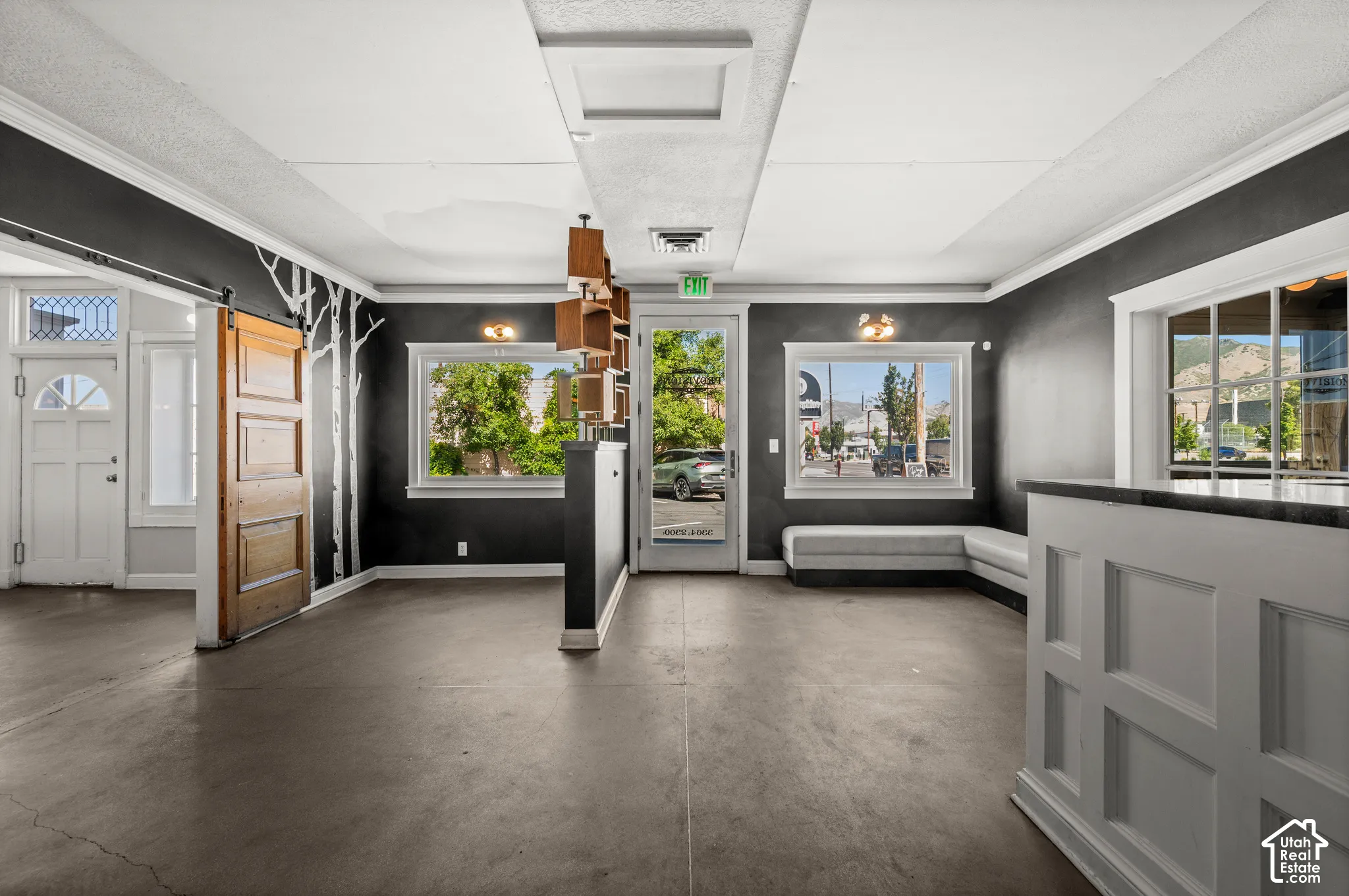 Open concept interior featuring dark-toned flooring, white crown molding, and multiple windows