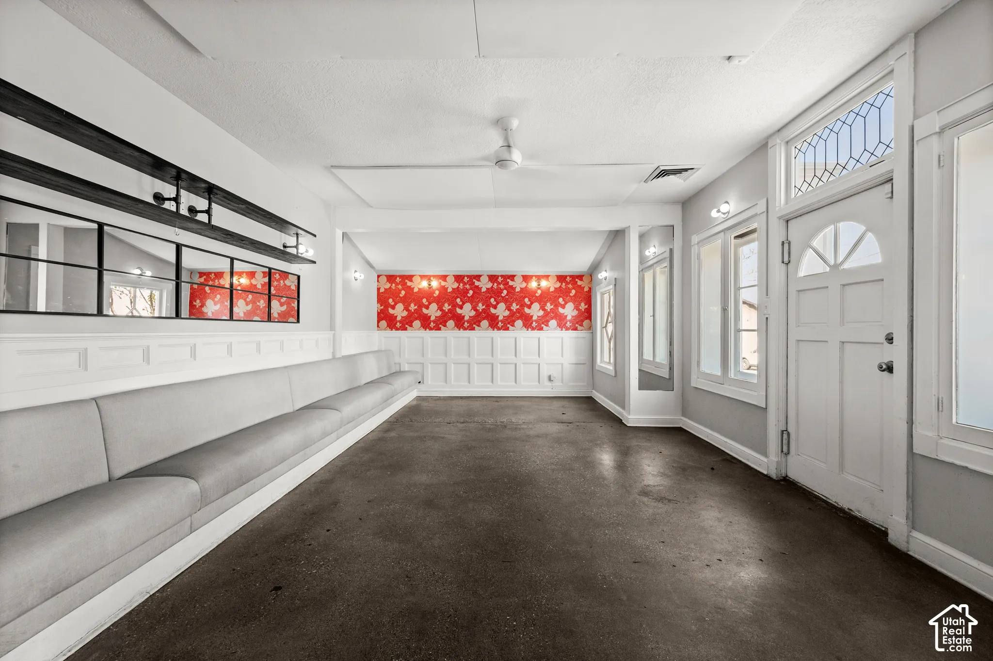 Paneled wainscoting, decorative red wall covering, solid surface flooring, transom windows, and an arched-top front door