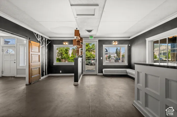 Open concept interior featuring dark-toned flooring, white crown molding, and multiple windows