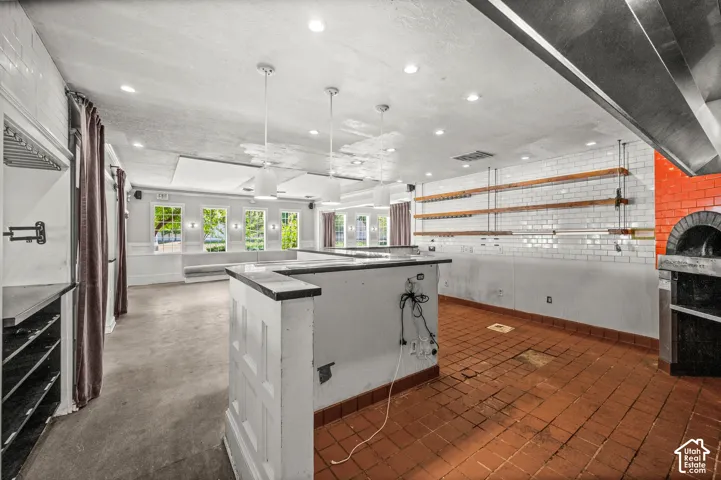 Commercial space featuring a built-in brick oven, subway tile walls, wood shelving, recessed lighting, and multiple windows
