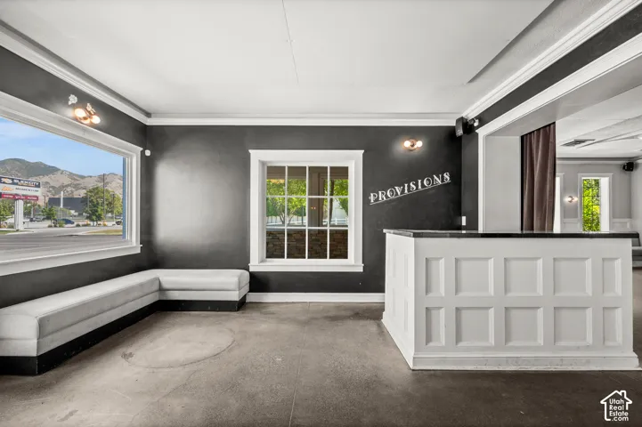 Interior space featuring a white paneled bar with a dark countertop, expansive windows with white trim, and a built-in upholstered bench seating