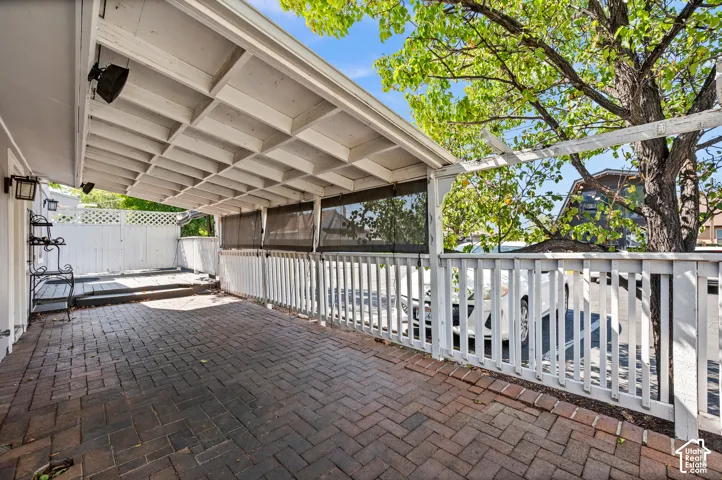 Covered patio with a herringbone brick paver floor, slatted wood ceiling, and white wood railing