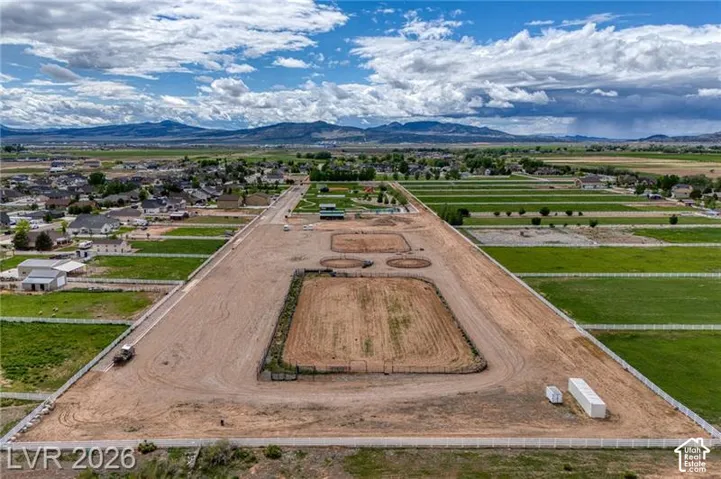 Expansive cleared land featuring multiple fenced arenas, a long, flat dirt track, and partially cleared surroundings