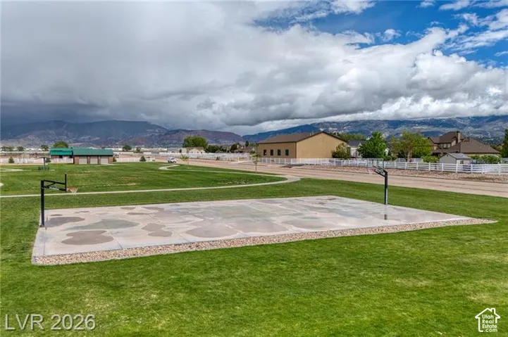 Expansive green space featuring a concrete basketball court with two hoops, surrounded by a manicured lawn