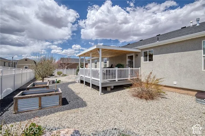 Expansive gravel landscaping with raised garden beds and a white vinyl fence