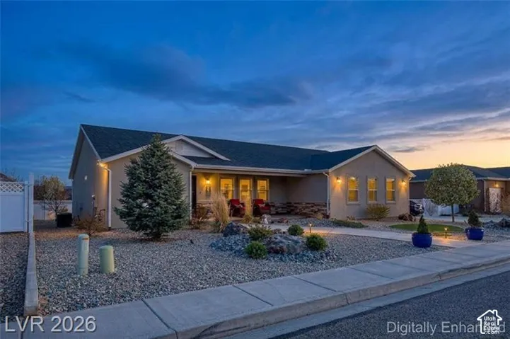 Stucco exterior with stone accenting, covered front entry, low-maintenance gravel landscaping, and concrete sidewalk