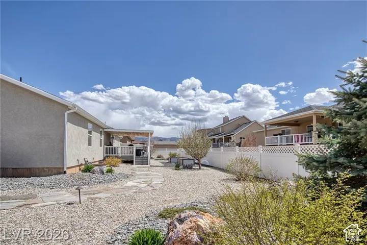 Expansive backyard with gravel landscaping, stone paver pathway, and a covered deck