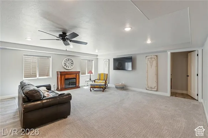 Recessed lighting, ceiling fan, fireplace with wood mantel, light-toned carpeting, and white trim