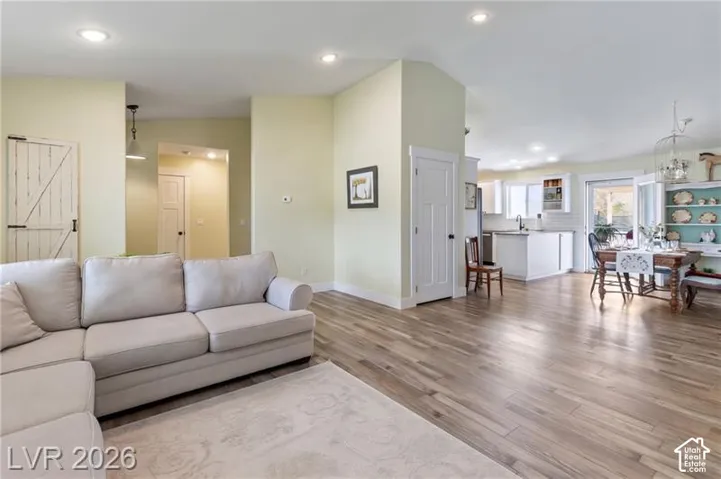 Recessed lighting, wood-finish flooring, white shaker-style cabinetry, a kitchen island, and a sliding glass door