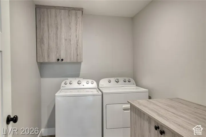 Integrated laundry area with overhead storage cabinetry, a built-in folding counter, and coordinating wood-finish cabinetry