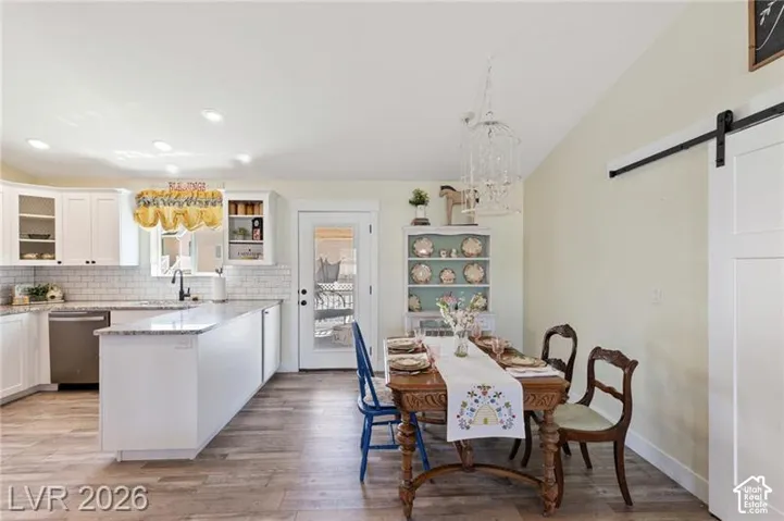 White kitchen cabinetry with a light stone countertop, subway tile backsplash, and stainless steel dishwasher