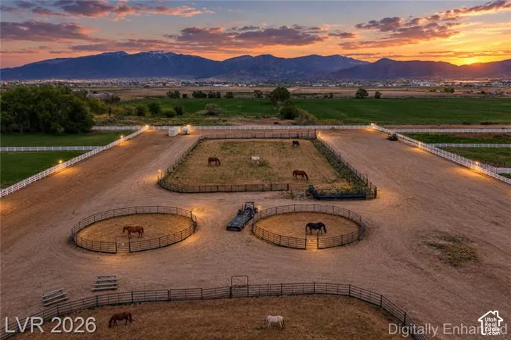Expansive equestrian property featuring multiple fenced paddocks, two round pens, and mountain scenery
