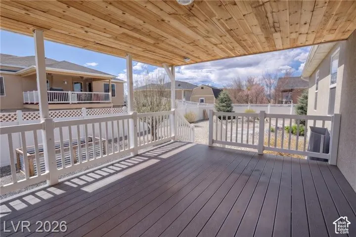 Covered patio featuring a wood-finish ceiling, composite decking, and white railing