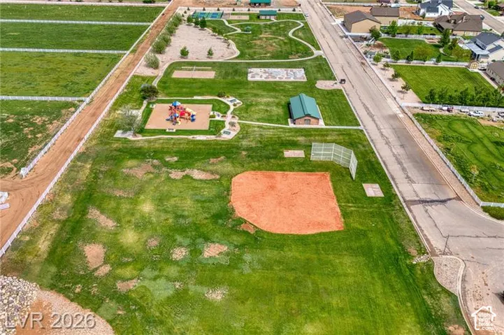 Expansive green space featuring a baseball diamond, playground structure, and walking paths