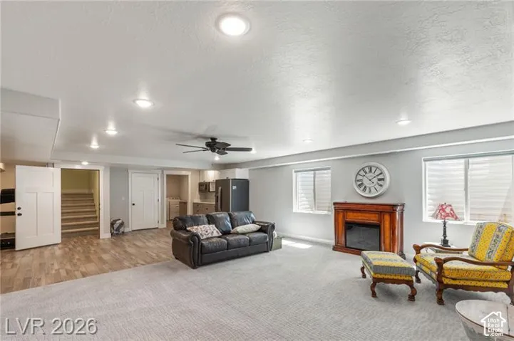 Expansive living area featuring light gray walls, recessed lighting, and a dark wood-finish mantel