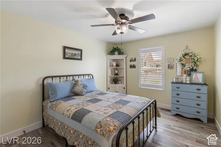 Wood-finish flooring, ceiling fan with integrated lighting, window with plantation shutters, and a corner built-in cabinet