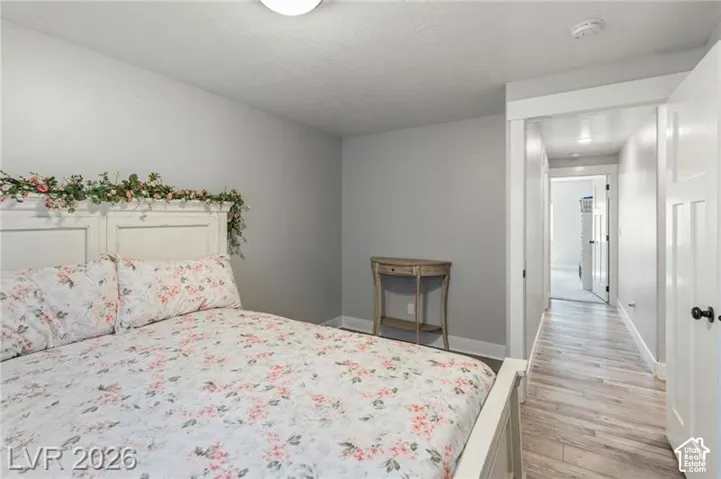 Light gray wall paint, wood-finish flooring, white trim, and a white interior door with dark hardware