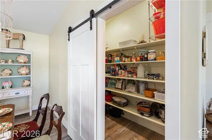 Barn door entry to an expansive pantry with multiple shelves and wood-finish flooring