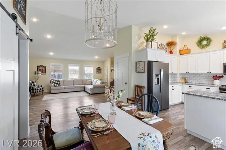 Open concept living area featuring a kitchen with white cabinetry, stainless steel refrigerator, and granite countertops