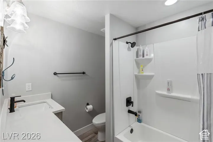 Bathroom featuring a bathtub with shower, white shower surround, and built-in shelving