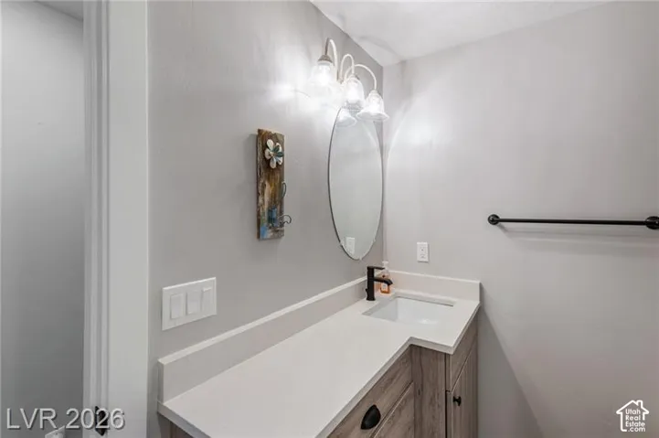 Vanity with wood-finish cabinetry, light-toned countertop, integrated sink, and matte black faucet