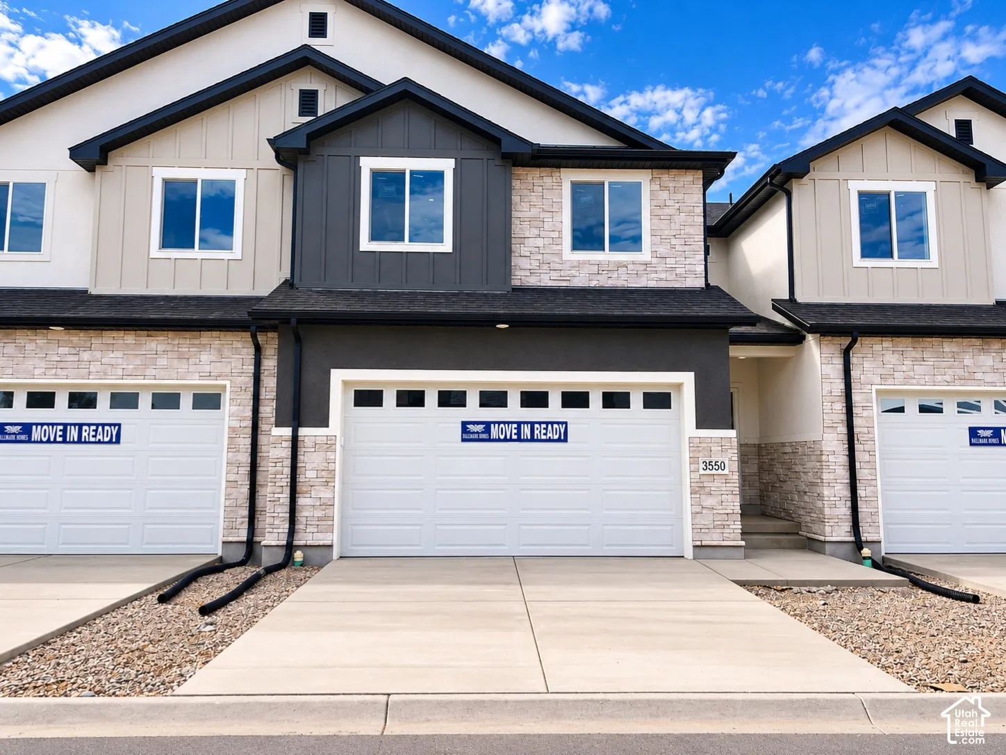 Exterior featuring stone veneer and vertical siding accents, individual garages, and concrete driveways