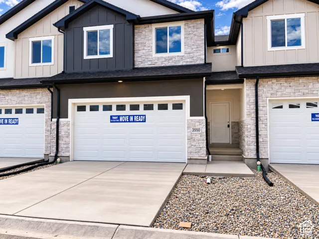 Contemporary townhouse exterior featuring a white paneled entrance door, attached garage, and stone facade accents