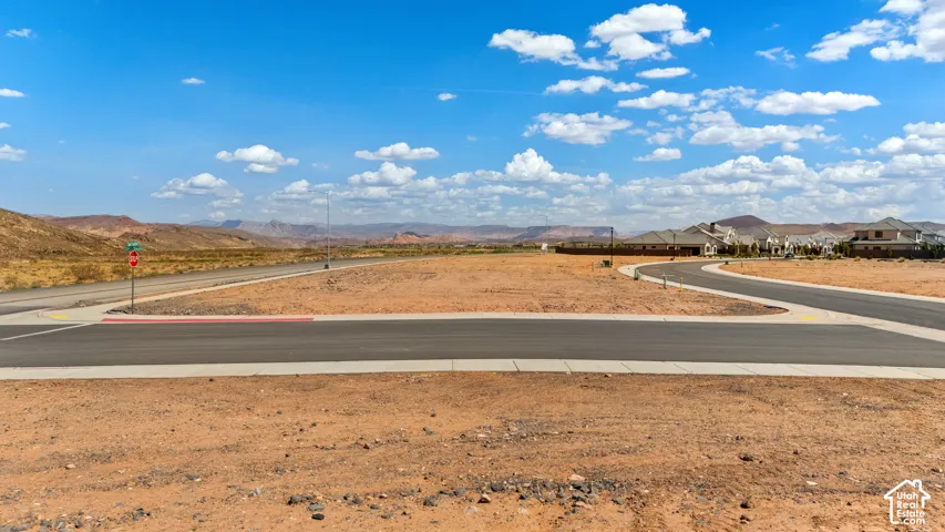 Expansive desert landscape with paved roadways, clear blue sky, and distant mountain ranges