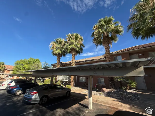 Covered parking structure with multiple spaces, featuring a metal roof and concrete support columns