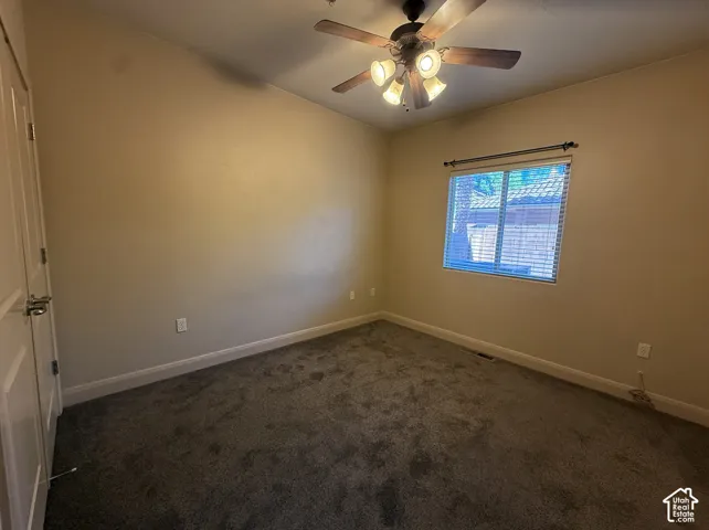 Plush carpet flooring, a window with horizontal blinds, a ceiling fan with integrated lighting, and a paneled door