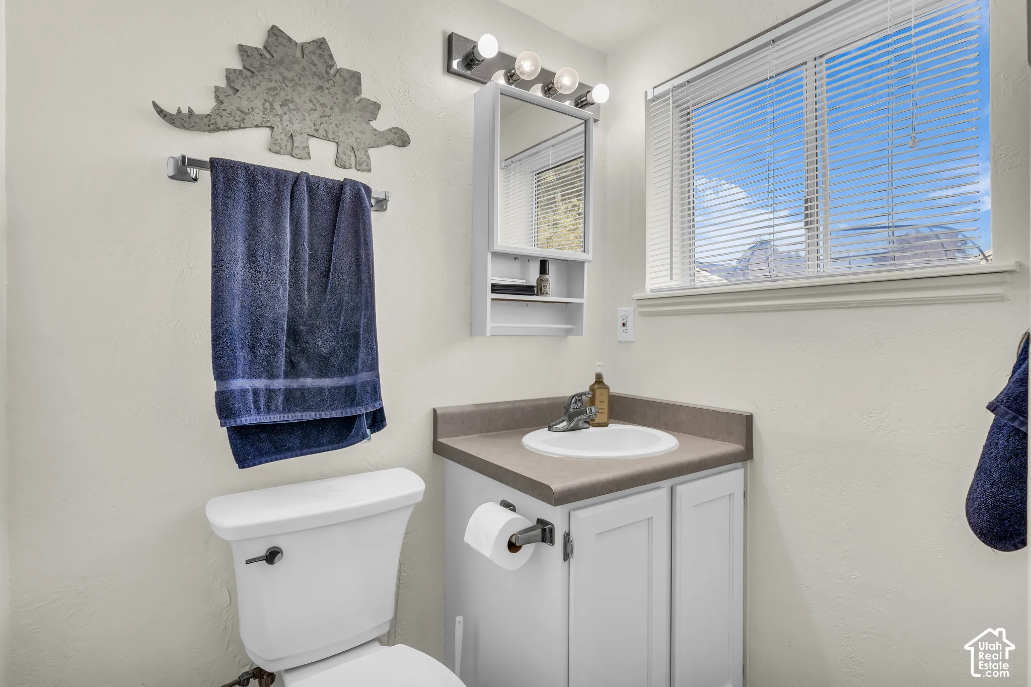 Vanity with an integrated sink, built-in medicine cabinet, and a window with blinds