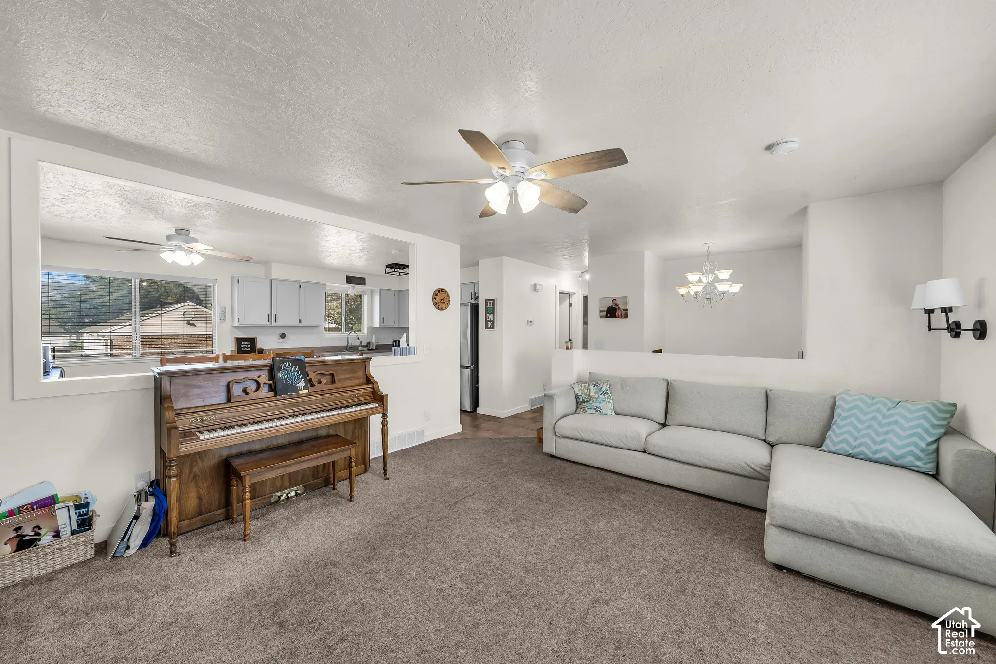 Open-concept living area featuring a ceiling fan, wall sconces, and a pass-through window to the kitchen