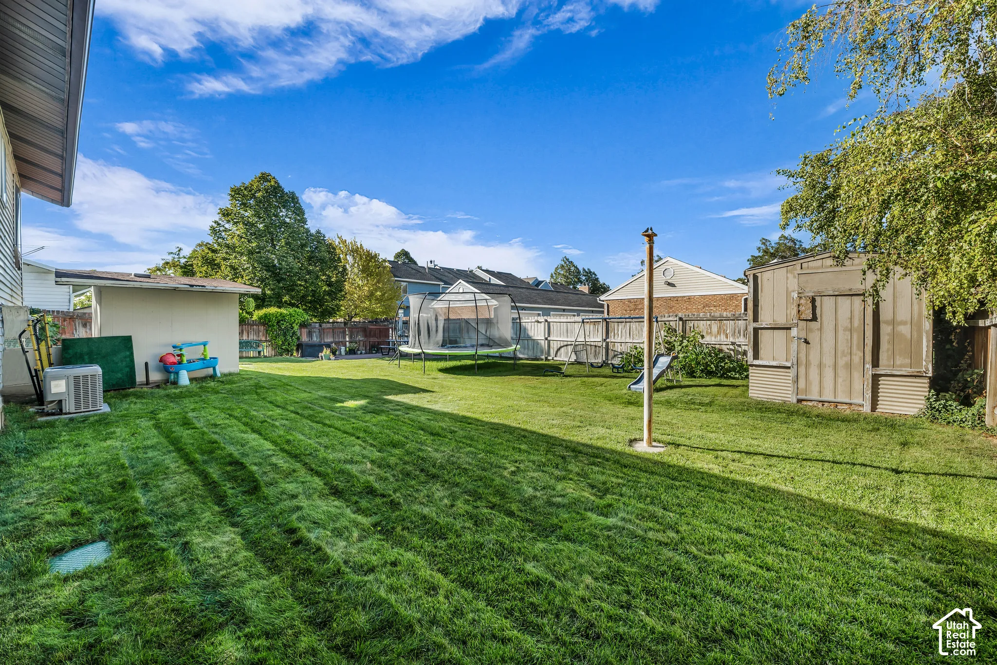 Expansive grassy yard with a detached shed and privacy fencing
