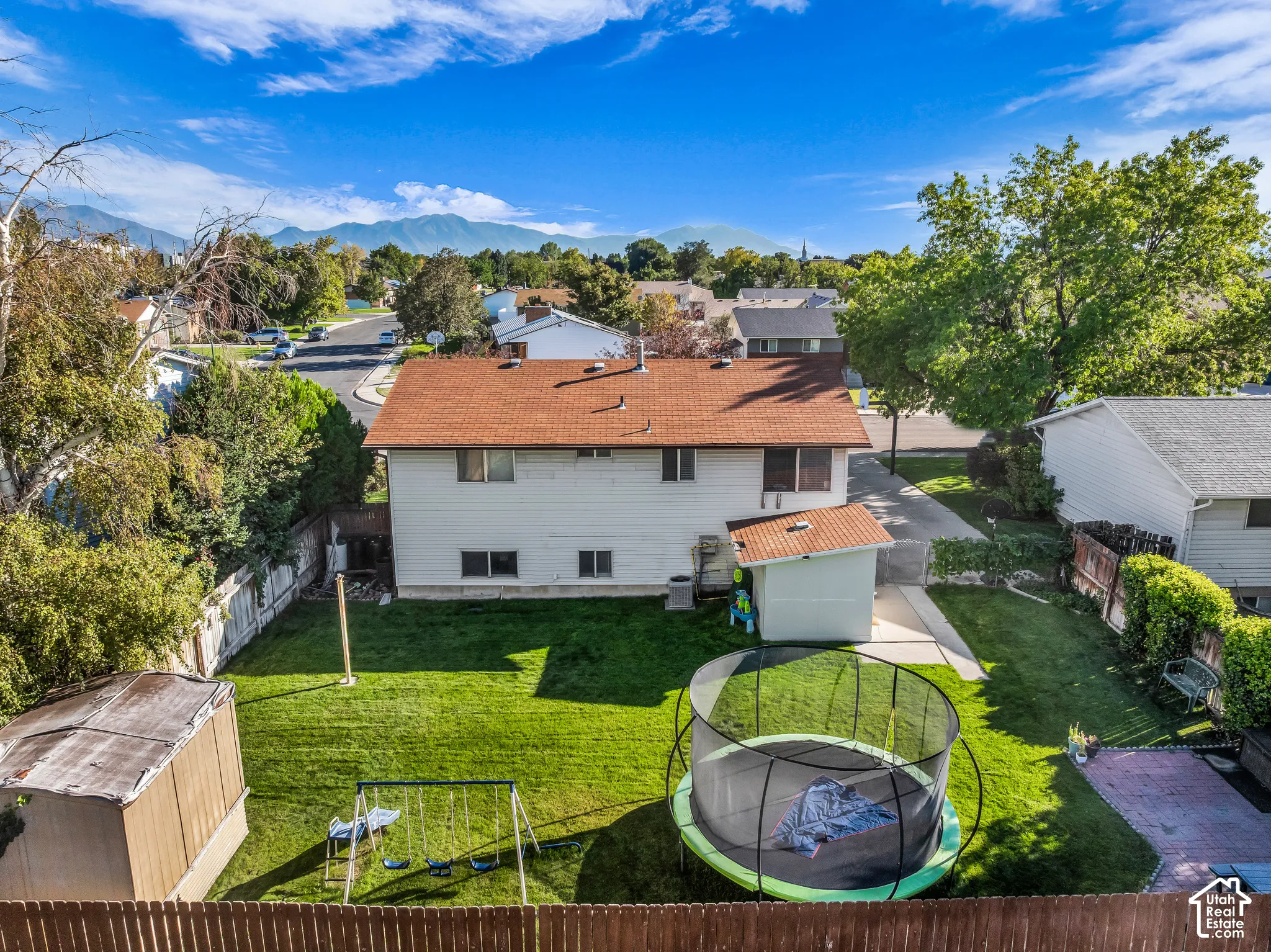 Expansive backyard featuring a manicured lawn, mature trees, and a privacy fence