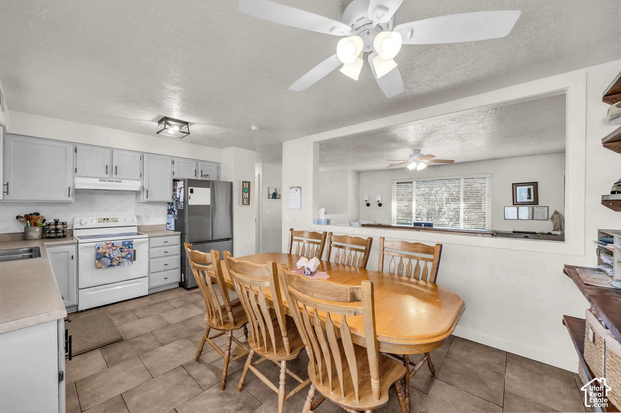 Kitchen featuring white cabinetry, tile flooring, and a pass-through opening to another room