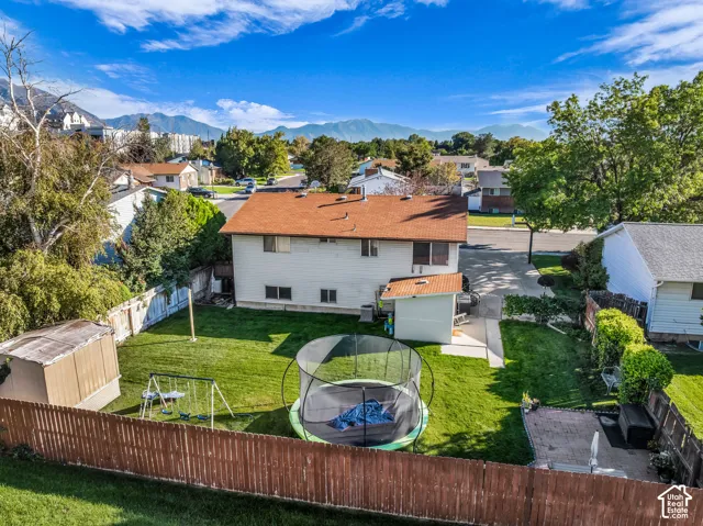 Expansive fenced backyard featuring a manicured lawn, two storage sheds, and a paved patio area