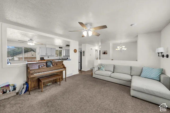 Open-concept living area featuring a ceiling fan, wall sconces, and a pass-through window to the kitchen