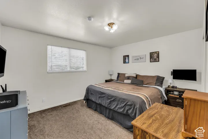 Carpeted room with a ceiling-mounted light fixture and a window with blinds
