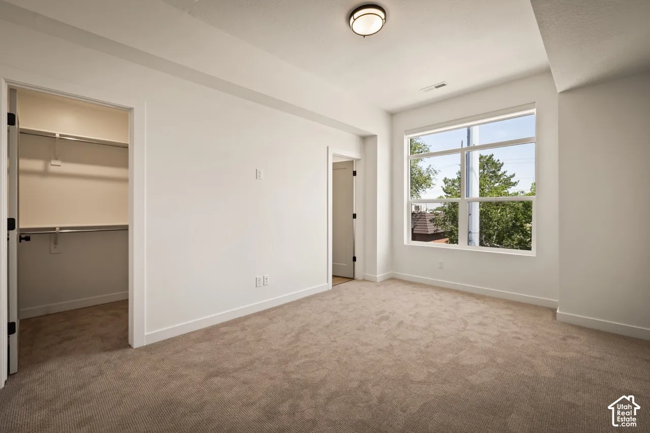 Neutral carpeting, white painted walls, and a large multi-pane window