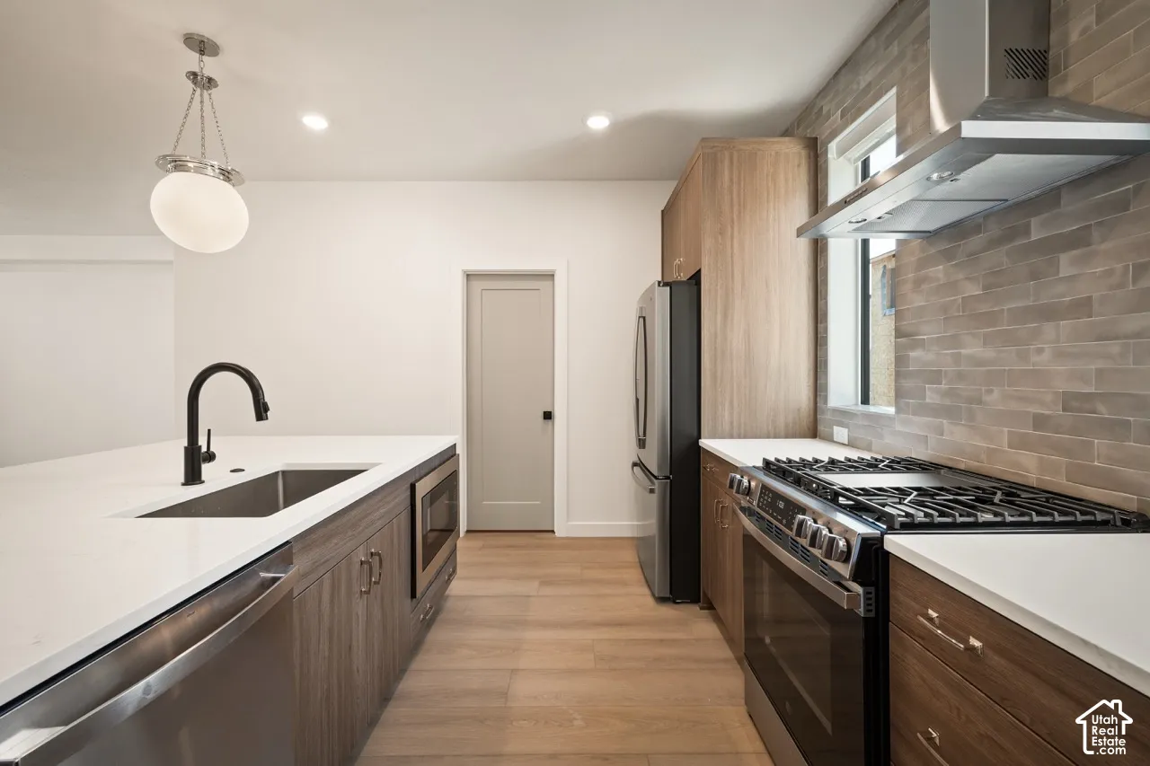 Modern kitchen featuring wood-finish cabinetry, stainless steel appliances, white countertops, and a tiled backsplash
